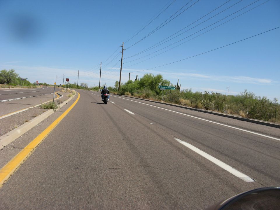 Motorcycle riding on a highway in a desert landscape under a clear blue sky