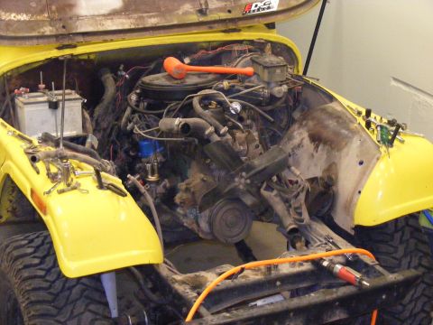 1981 Jeep CJ7 - Engine bay of a 1981 Jeep CJ7 undergoing repairs, with the hood fully open.