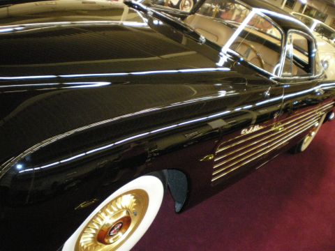 1998 Ford Crown Victoria - Side detail of a black custom coupe with gold trim, Cadillac script and gold wire wheels with whitewalls.