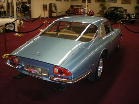 1998 Ford Crown Victoria - Light blue Ferrari fastback coupe shown from the rear three-quarter on a red carpet among classic cars.