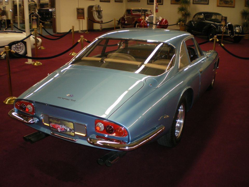 Rear three-quarter view of a light blue Ferrari fastback coupe in a museum