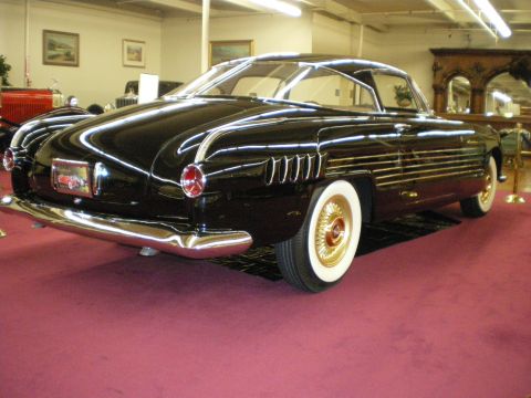 1998 Ford Crown Victoria - Black streamlined custom coupe shown from the rear three-quarter with chrome trim and gold wire wheels.