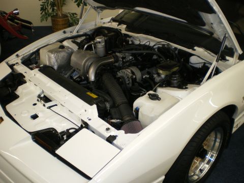 1998 Ford Crown Victoria - Open engine bay of a white car showing a turbocharged engine with a cone air filter and exposed plumbing.