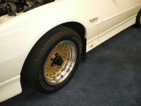 1998 Ford Crown Victoria - White car front fender showing a gold mesh wheel, Goodyear Eagle tire and a Turbo emblem on the body.
