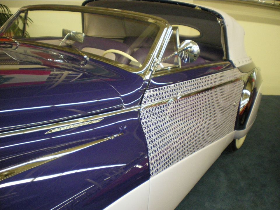 Side profile of a purple and white classic convertible with chrome trim, top up