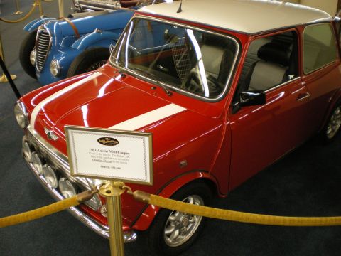 1998 Ford Crown Victoria - red classic Mini Cooper with white roof and rally lamps on museum display with an information placard out front.