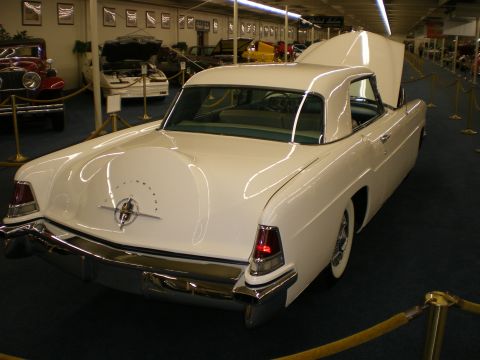 1998 Ford Crown Victoria - Rear three-quarter view of a white Continental hardtop coupe with chrome bumper and spare-tire trunk bulge in a museum.
