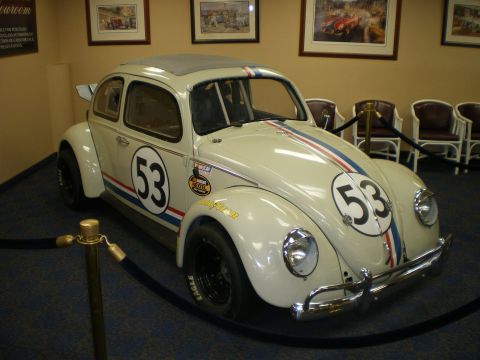 1998 Ford Crown Victoria - Front three-quarter of a cream number-53 Herbie VW Beetle with rear wing and racing decals on museum display.