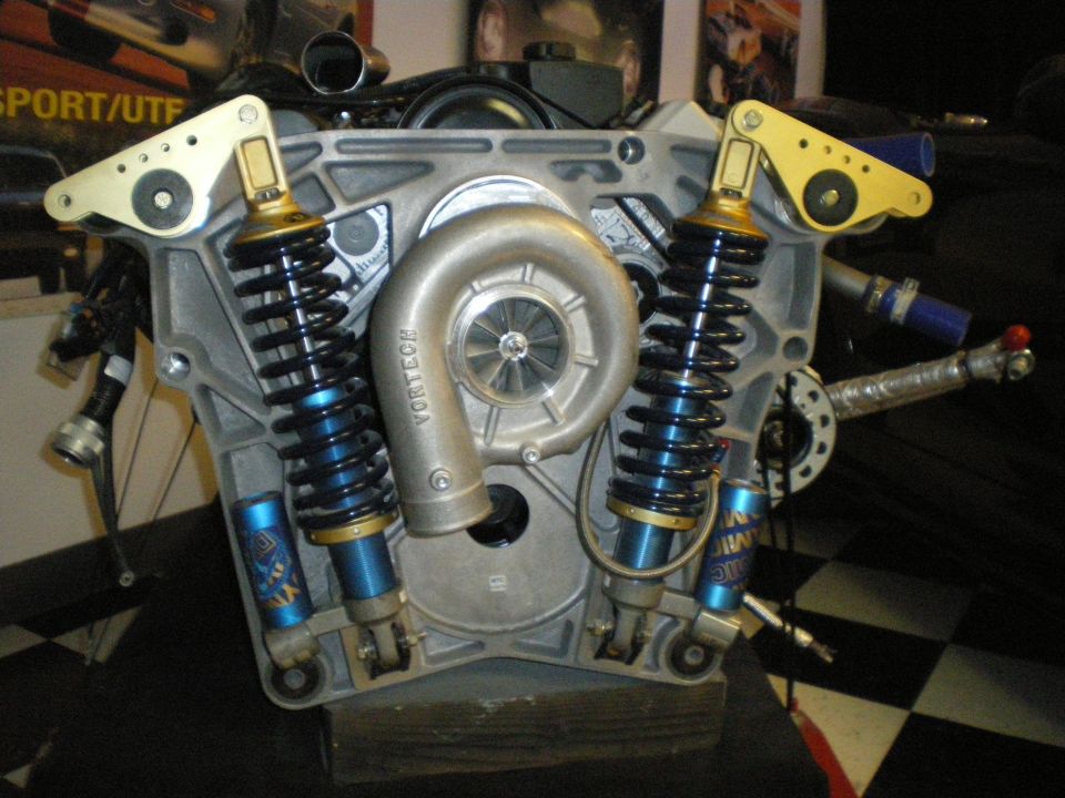 Cutaway race engine block with twin coilover shocks mounted on a stand