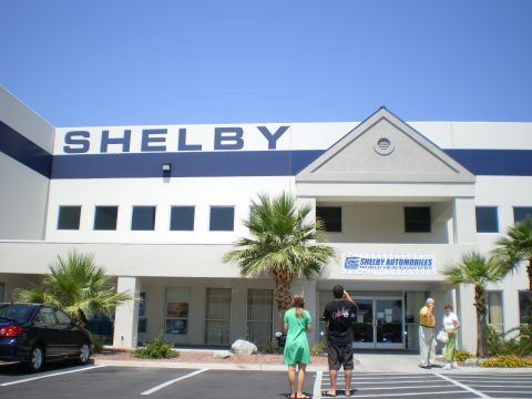 1998 Ford Crown Victoria - Exterior of the Shelby Automobiles World Headquarters building with large SHELBY signage, palms and visitors outside.