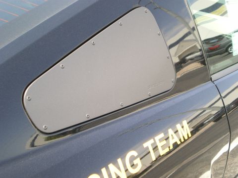 1998 Ford Crown Victoria - Close-up of a black sports car's bolted-on quarter-window blanking panel above gold lettering reading TEAM.