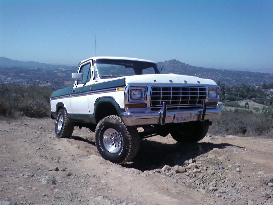 1978 Ford Bronco parked on a dirt hill with a scenic background