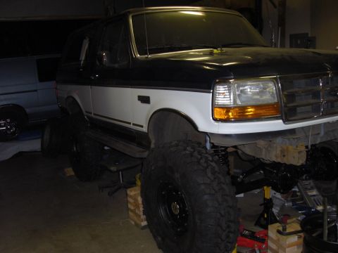 1993 Ford Bronco - This two-tone Ford Bronco is heavily modified with a suspension lift and oversized tires, suggesting off-road capabilities.