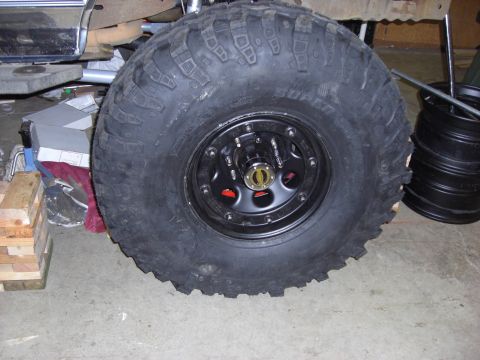 1993 Ford Bronco - Close-up of a large off-road tire and wheel assembly, with a portion of a vehicle in the background.