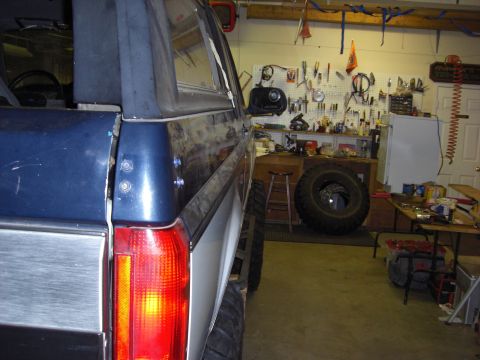 1993 Ford Bronco - Side view of a 1993 Ford Bronco parked in a workshop with tools and a spare tire.