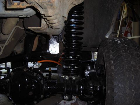 1993 Ford Bronco - Undercarriage view of a vehicle's suspension and axle components, with a prominent black coil spring.