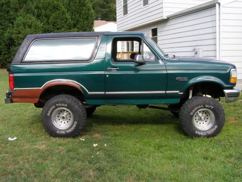 1993 Ford Bronco - Side view of a lifted 1993 Ford Bronco with aftermarket wheels and a two-tone paint scheme.