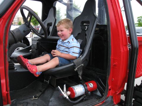 1994 Ford Bronco - A young boy smiles from the passenger seat of a red off-road vehicle, which is equipped with racing seats and a fire extinguisher.