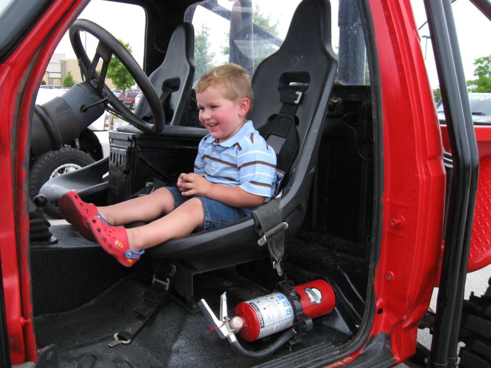 Interior of red off-road vehicle with child in racing seat and fire extinguisher