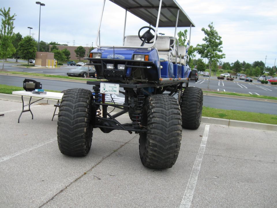 Blue lifted golf cart with large off-road tires parked in a lot. 'MEMPHIS' text on front