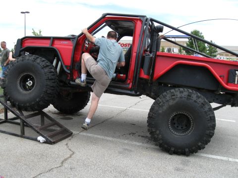 1994 Ford Bronco - A person enters a custom-built off-road truck, which is positioned on a ramp.