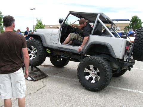 1994 Ford Bronco - A modified Jeep Wrangler is parked on a ramp, with a man sitting in the driver's seat.