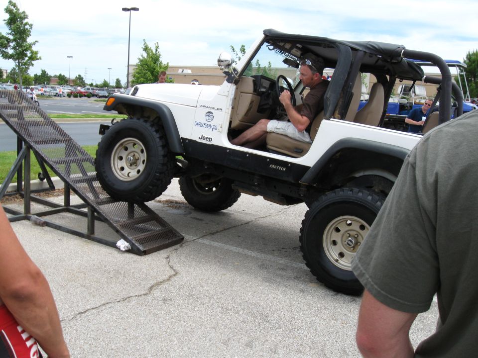 White Jeep Wrangler driving up a metal ramp