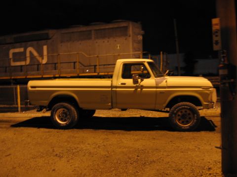 1967 Ford Mustang - A yellow 1975 Ford F250 pickup truck is parked at night with a CN train in the background.