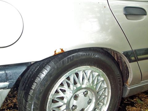 1989 Ford Thunderbird - Close-up of a car's rear wheel well with visible rust. The model year is uncertain from this view.