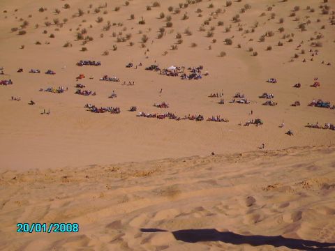 1990 Ford Bronco - A wide view of a desert gathering with many vehicles and people spread across the sand dunes.