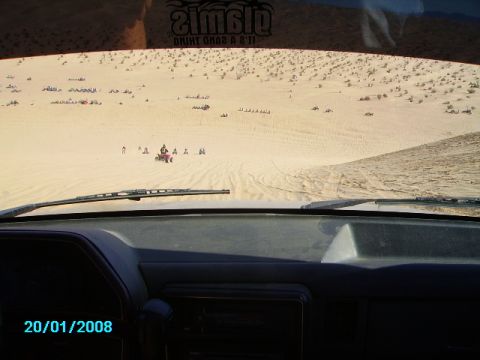 1990 Ford Bronco - Driving through sand dunes with multiple ATVs and vehicles enjoying the desert landscape.