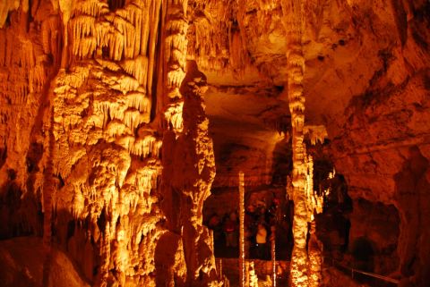 1996 Ford Bronco - A view inside a cave, a dense formation of stalactites and stalagmites, illuminated by artificial orange lighting.
