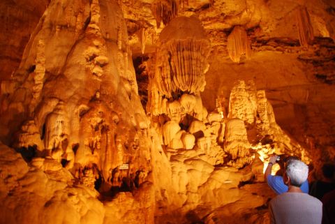 1996 Ford Bronco - People explore a cave filled with impressive natural rock formations illuminated by artificial lights.