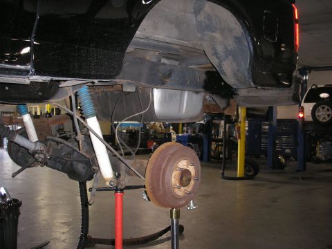 1995 Ford Bronco - Underbody view of a vehicle in a repair shop, with another vehicle on a lift in the background.