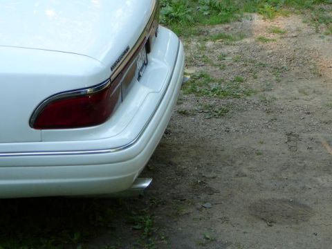1997 Mercury Grand Marquis - The rear of a white 1997 Mercury Grand Marquis shows its chrome bumper trim and a visible exhaust tip.