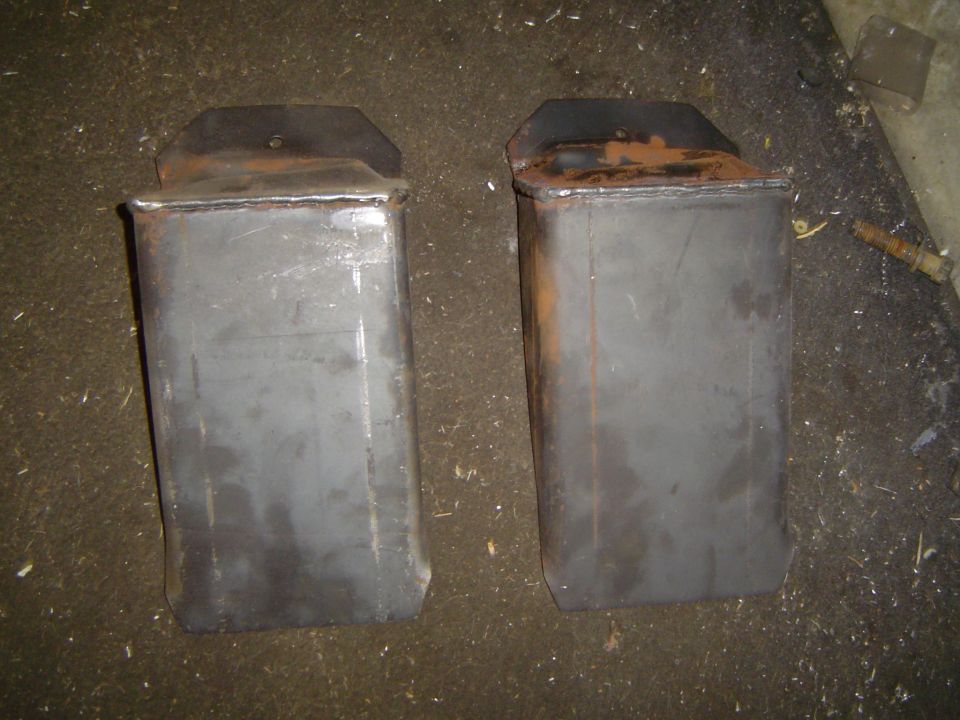 Pair of shop-fabricated bare steel weld-up brackets on a concrete shop floor