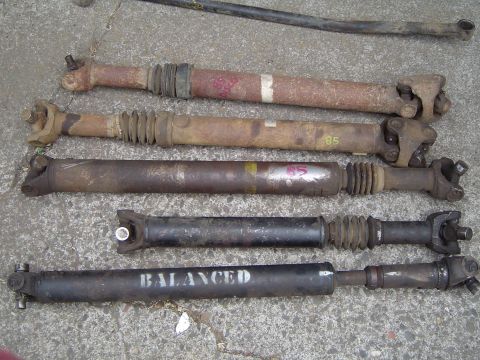 1989 Ford Bronco - A collection of drive shafts, some with visible markings, are displayed on a concrete surface.