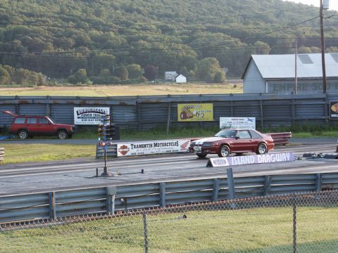 2001 Mercury Grand Marquis - Two vehicles at Island Dragway, one a red coupe on the track, the other a red SUV off to the side.