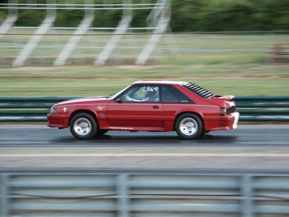 Red Fox-body Mustang GT hatchback with window louvers running down a drag strip