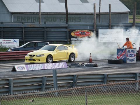 2001 Mercury Grand Marquis - Yellow 2001 Ford Mustang Cobra performs a burnout at Island Dragway, with another car visible in the background.
