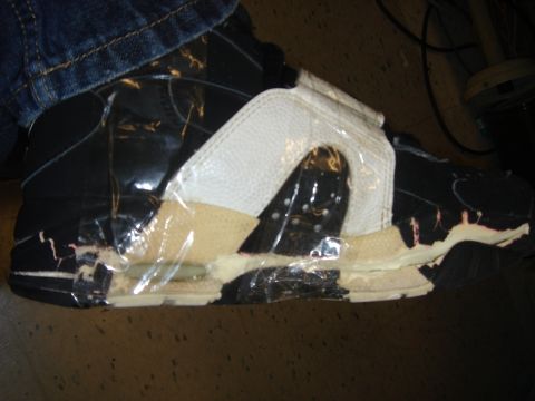 1990 Ford Bronco - A damaged shoe is covered in clear plastic wrap, revealing exposed foam and wear.