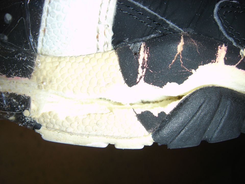 Close-up of a damaged shoe sole with torn black material exposing yellow foam