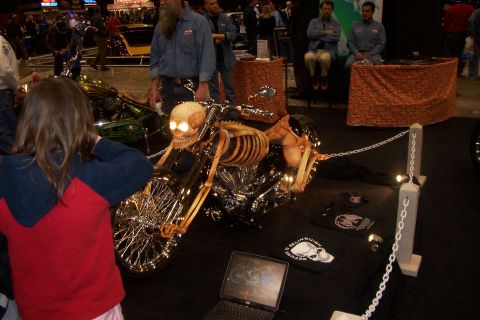 1970 Ford Ranchero - A custom motorcycle a skeleton rider with glowing eyes is displayed at an event. The SuperMotors.net logo is visible in the lower right cor…