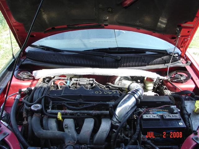 red car engine bay with aftermarket intake and battery