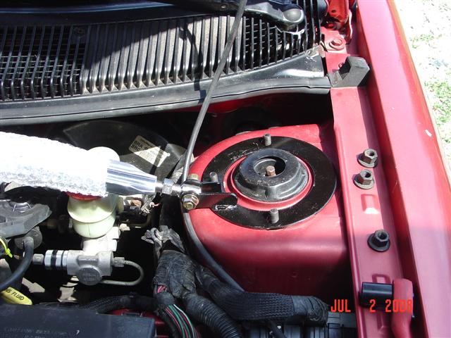 1997 Dodge Neon engine bay showing red strut tower, brake fluid reservoir, and wiring