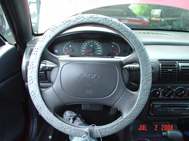 Interior view of a car with a gray steering wheel cover and 'neon' emblem