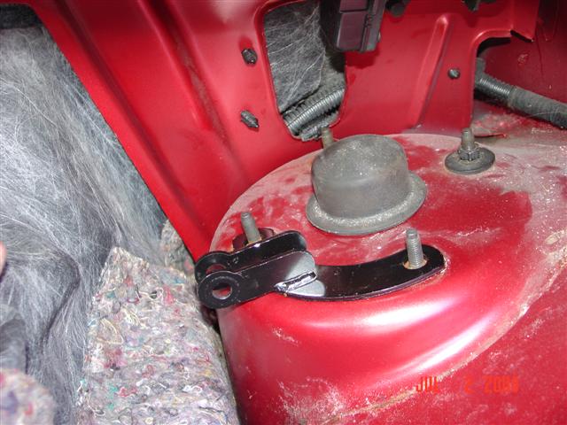 Red car engine bay showing suspension mount and rubber boot