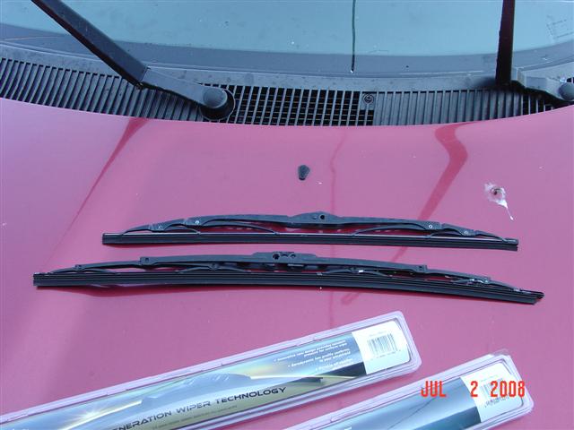 Two windshield wiper blades on a red car hood