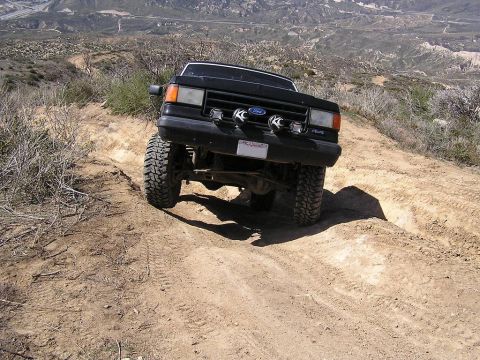 1990 Ford Bronco - Black 1990 Ford Bronco navigating a challenging off-road course in a mountainous, arid landscape.