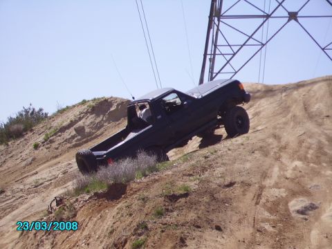1990 Ford Bronco - 1990 Ford Bronco navigating an off-road trail on a sunny day.